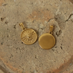 Macro detail of a gold-plated titanium unicorn sun pendant with holy spirit dove relief