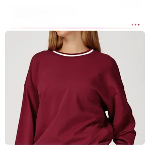 Close-up of a burgundy sweatshirt featuring a ribbed round neck with white contrast stripes