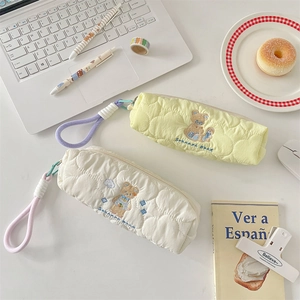 Close-up of quilted pencil case with bear embroidery and soft carry handle on a desk