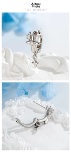 Detailed close-up of a silver star charm huggie earring with zircon inlay detail