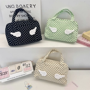 Three polka dot travel cosmetic bags with plush wing details on a white display stand