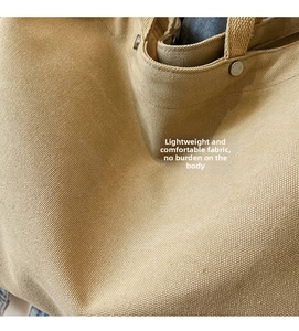Close-up of khaki canvas tote bag showing thick fabric texture and metal rivet detail