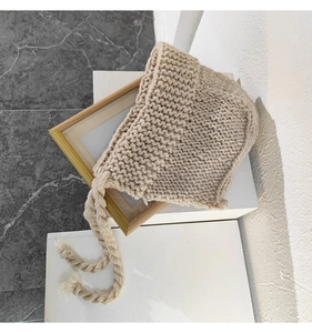 Gros plan sur un bonnet en grosse maille fait main avec texture tressée et lanières