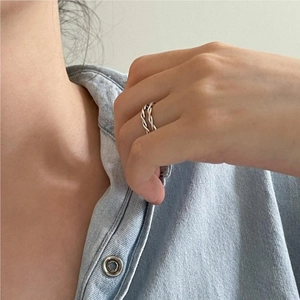 Detail of twisted double-layer silver ring worn on index finger with denim shirt