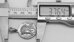Detailed measurement of the vintage steel pendant diameter showing 37.64 mm on a digital caliper
