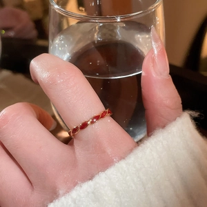 Detail of red enamel and gold plated twisted rope ring worn in a lifestyle scene