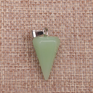 Macro shot of green faceted crystal cone pendant with silver metal clasp on linen