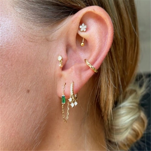 Detail of gold floral studs and green emerald drop earrings with sparkling zircon accents