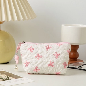 White quilted makeup bag with pink bow pattern, pearl charm, and top handle zipper
