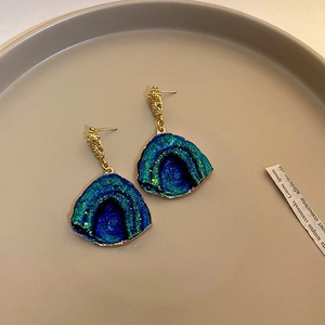 Vue détaillée des boucles d'oreilles en résine sarcelle avec monture en métal doré
