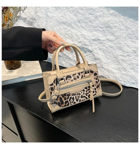 Detalle de bolso de piel beige con panel de leopardo y bolsillo frontal con cremallera