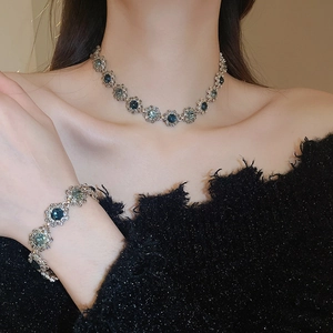 Macro shot of silver flower necklace and bracelet with dark blue gemstones on model