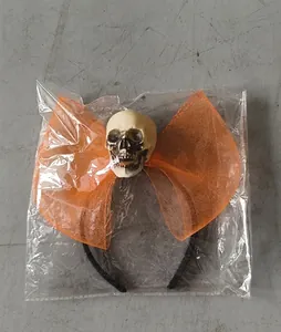 Detail of Halloween skeleton head headband with orange mesh bow in protective packaging