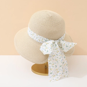 Vue détaillée de la texture en paille tressée et du ruban à fleurs sur le chapeau d'été