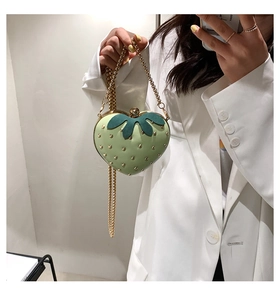 Detail of light green strawberry bag with gold rivets and metallic chain strap