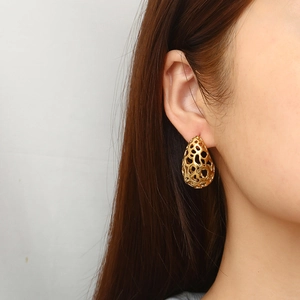 Boucles d'oreilles goutte à grille évidée en acier doré 18K sur un modèle