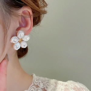 Dettaglio di un orecchino floreale in perla vintage con stame dorato su una modella