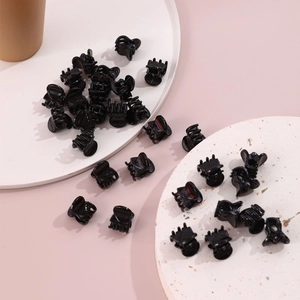 Multiple small black plastic mini claw clips on clean minimalist white pedestals