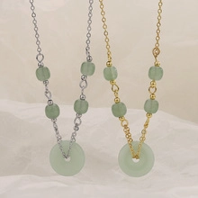 Close-up of gold and silver layered necklaces featuring green jade donut pendants