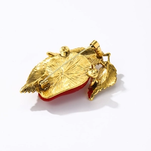 Back view of a red strawberry enamel brooch with a golden alloy base on a white background