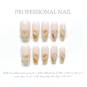 Detailed view of handmade press-on nails with amber stones and silver glitter on nude base