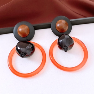 Detail of vintage round earrings with orange acrylic hoop and faux wood texture bead