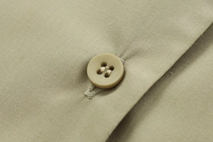 Macro shot of olive green poplin fabric texture and matching four-hole button detail