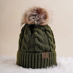 Detail of olive green cable knit beanie with faux fur pompom and brown leather logo patch