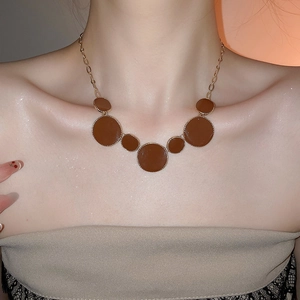 Détail d'un collier chaîne dorée vintage avec pendentifs ronds en résine sur un modèle