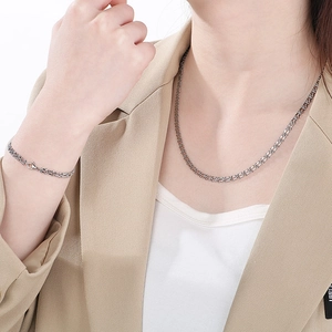 Close-up of stylish stainless steel music note necklace and bracelet set on a model