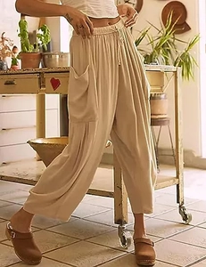 Détail d'un pantalon sarouel beige avec taille haute à cordon et grandes poches latérales
