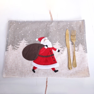 Christmas burlap table mat featuring Santa Claus on a white wood surface with cutlery