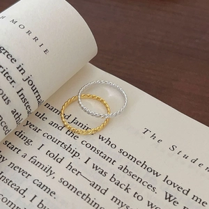 Set of gold and silver S925 sterling silver twisted rope rings on an open book page
