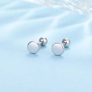 Macro shot of silver stud earrings with secure screw-back ball closure on satin background
