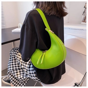 Neon green crescent shoulder bag styled with black outfit in a modern cafe setting
