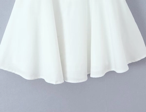 Detailed view of the elegant draped hemline on a minimalist white summer dress