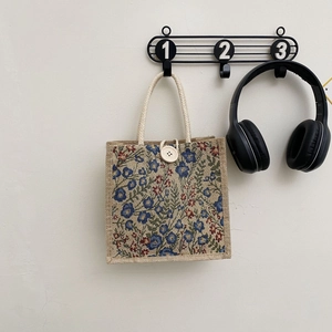 Detail of vintage floral jacquard tote bag with woven rope handles and wooden button