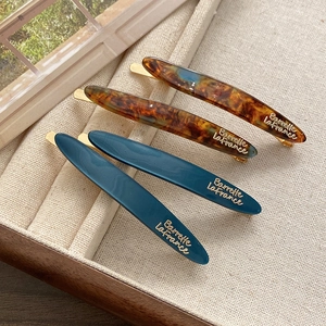 Detailed set of tortoise and green acetate hair barrettes on elegant display tray