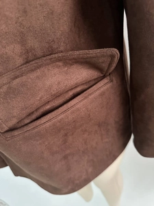 Detail view of the flat stitching and flap pocket on a brown faux suede blazer