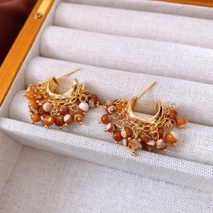 Detail of vintage gold C-shape earrings with brown and white beaded fringe tassels