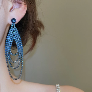 Gros plan de boucles d'oreilles élégantes à pampilles en strass bleu sur un mannequin