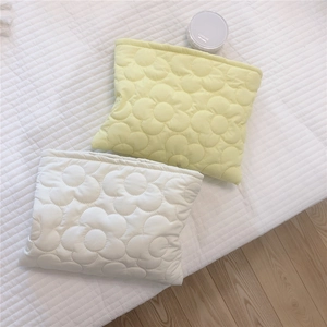 Detail of floral quilted cosmetic bags in light yellow and off-white soft fabric
