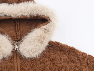 Dettaglio di una giacca in pile teddy marrone con collo in pelliccia e cerniera in metallo