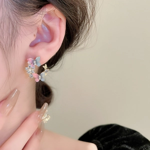 Detailed close-up of a sweet butterfly and flower earring with pink blue gradient petals