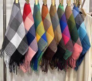 Close-up of multicolored plaid cashmere scarves with soft tassels on a display rack