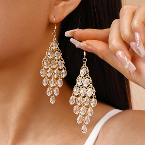 Detail of elegant gold crystal teardrop fringe earrings worn on a female model