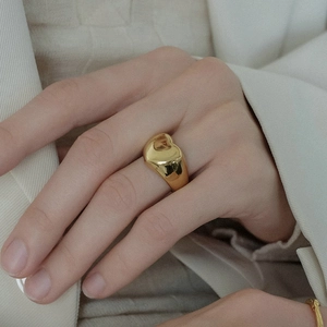 Detailansicht eines breiten goldenen Rings am Zeigefinger mit glänzender Oberfläche