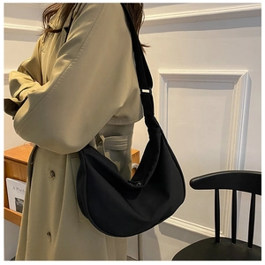 Detailed side view of a black crescent nylon crossbody bag with adjustable wide strap