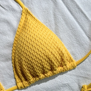 Dettaglio del tessuto a nido d'ape giallo su un top bikini a triangolo allacciato