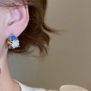 Detail view of retro denim fabric C-shaped earrings with floral pattern worn by a model